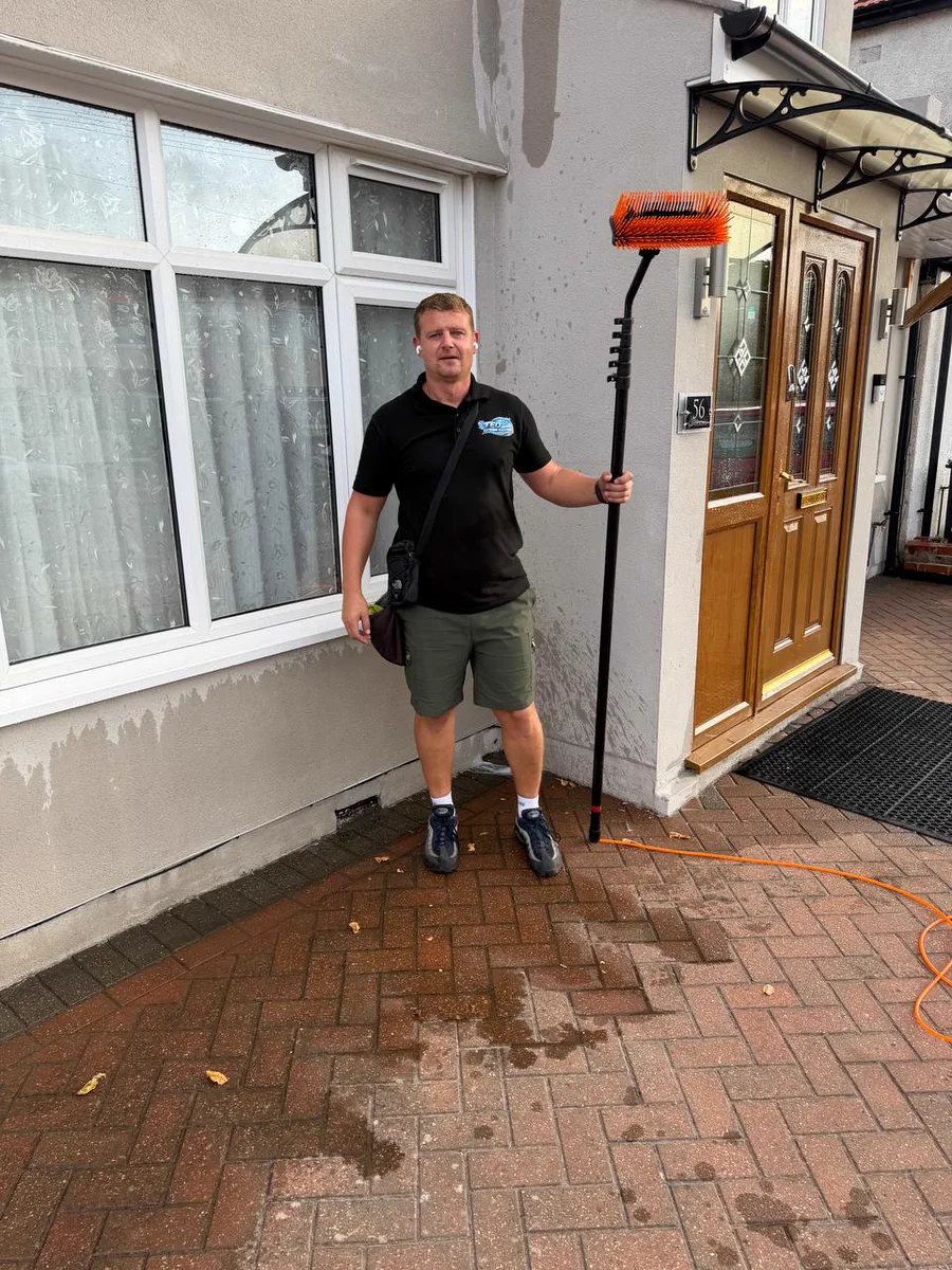 Teo, who runs Teo Exterior Cleaning, holding a water-fed pole outside a North London house